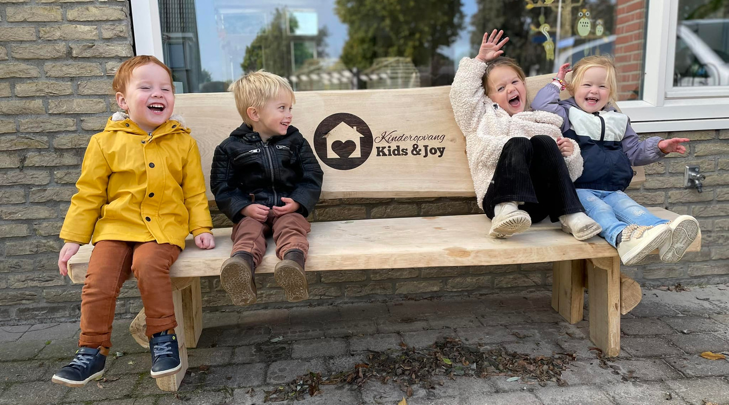 Lachende kinderen op het bankje van Kids & Joy
